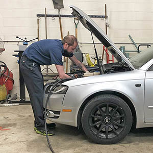 A Corentstone mechanic works on the engine of a car